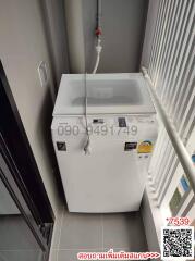 Compact white top-loading washing machine in a narrow laundry space