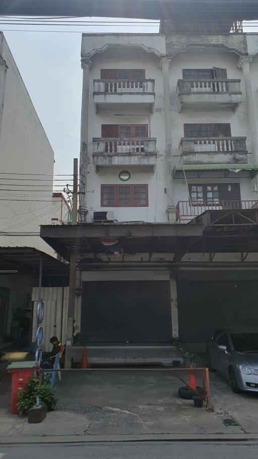 Urban multi-story residential building exterior with balconies and vehicles