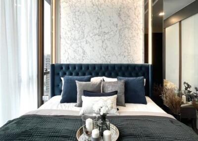 Elegant bedroom with blue tufted headboard and marble accent wall