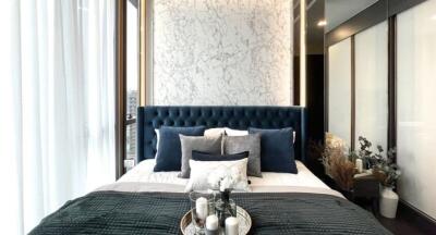 Elegant bedroom with blue tufted headboard and marble accent wall