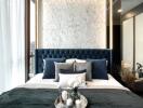 Elegant bedroom with blue tufted headboard and marble accent wall