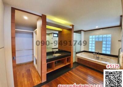 Spacious modern bathroom with separate tub and shower areas, equipped with large windows and hardwood flooring