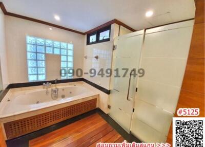Spacious bathroom with jacuzzi and wooden flooring
