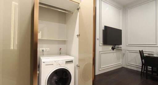 Compact laundry room with built-in appliances and adjacent dining area