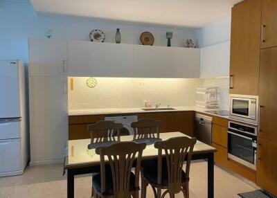 Modern kitchen with dining area, featuring wooden cabinets and integrated appliances