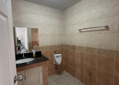 Modern tiled bathroom with urinal and sink