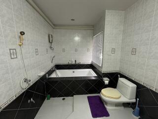 Spacious bathroom with large bathtub, modern fixtures, and tiled flooring