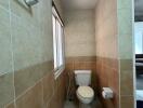 Spacious bathroom with neutral tiled walls and natural light