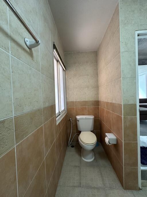 Spacious bathroom with neutral tiled walls and natural light