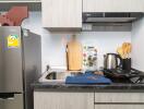 Modern compact kitchen with stainless steel appliances and wooden utensils