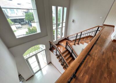 Bright and spacious staircase leading to upper floors with large windows and wooden banisters