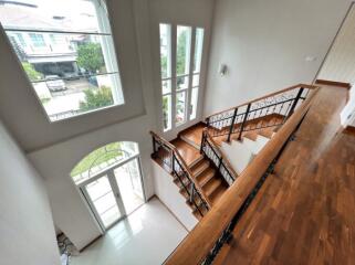 Bright and spacious staircase leading to upper floors with large windows and wooden banisters