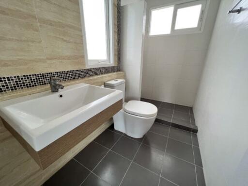 Modern bathroom with a large bathtub, toilet, and tiled walls