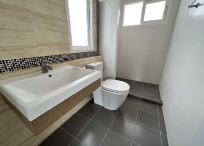Modern bathroom with a large bathtub, toilet, and tiled walls