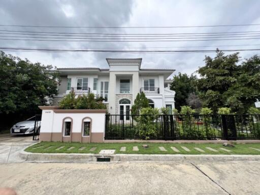 Elegant two-story house with a landscaped front yard and iron fence