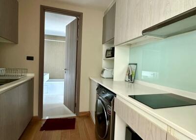 Modern compact kitchen with built-in appliances and adjacent laundry area