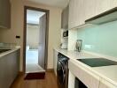 Modern compact kitchen with built-in appliances and adjacent laundry area