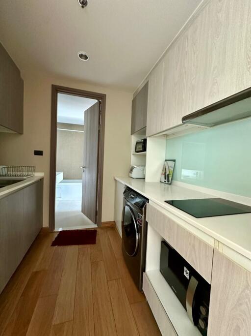 Modern compact kitchen with built-in appliances and adjacent laundry area