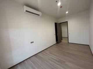 Spacious bedroom with wooden flooring and modern air conditioning unit
