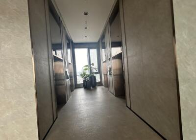 Modern hallway with marble floors and sleek mirrored walls leading to a well-lit room