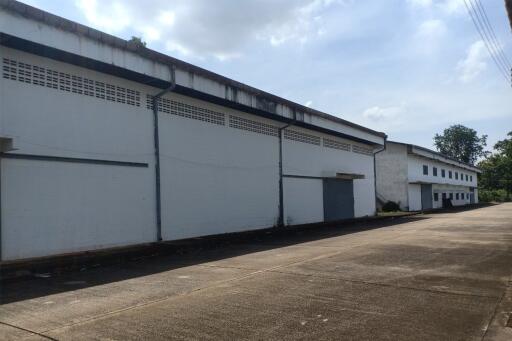 Exterior view of a large industrial warehouse with white walls and blue accents under a clear sky