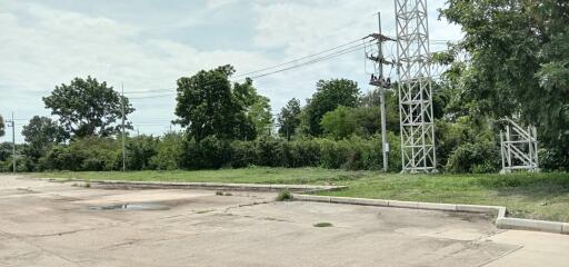 Spacious outdoor land near power transmission towers with green foliage