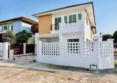 Modern two-story house with a white and wooden facade and gated entrance