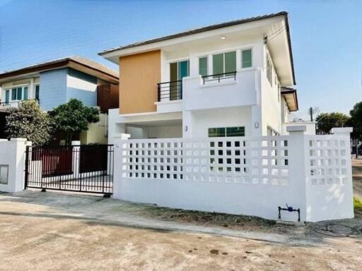 Modern two-story house with a white and wooden facade and gated entrance