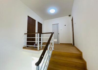 Bright upper floor hallway with wooden stairs and modern lighting