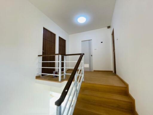 Bright upper floor hallway with wooden stairs and modern lighting