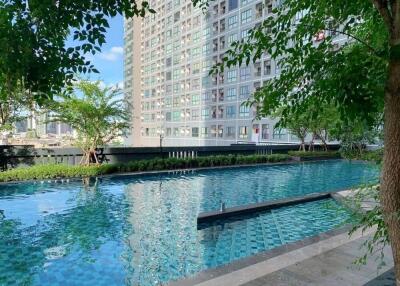 Luxurious outdoor swimming pool with modern high-rise apartment building in the background