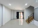 Spacious living room with sleek white tiles and staircase