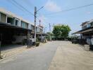 Street view of a row of modern townhouses with carports under a clear blue sky