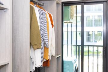 Modern entryway with an open wardrobe featuring stylish clothes and a view to the balcony