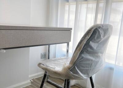 Modern bedroom with a desk and chair covered in protective plastic