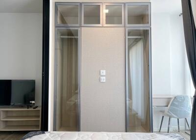 Modern bedroom with sliding glass wardrobe, wall-mounted TV, and minimalist decor