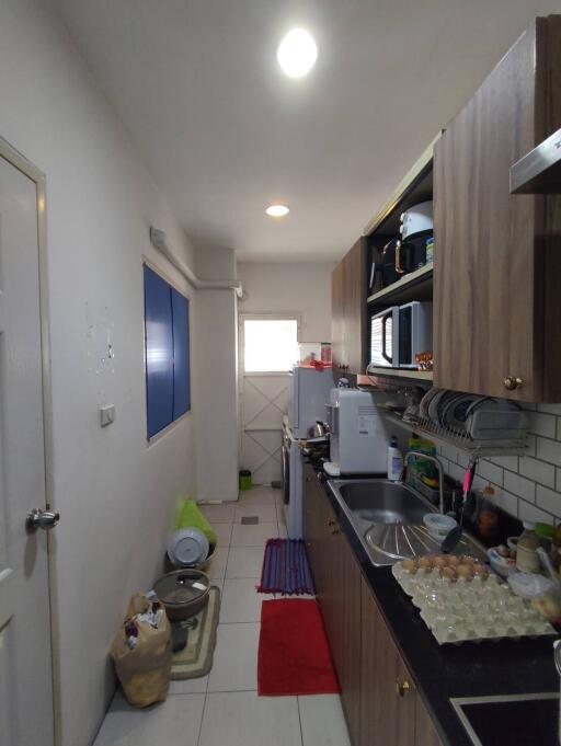 Narrow and modern kitchen with extensive cabinetry and white tile backsplash