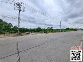 Empty land plot by a roadside with a pole and QR code