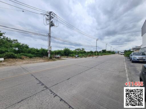 Wide street view in a suburban area with parked cars and overhead cables