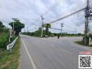 Wide asphalt road with utility poles and lush greenery on the sides