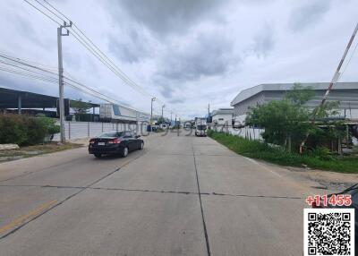 Wide asphalt road with cars and industrial buildings on a cloudy day