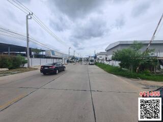 Wide asphalt road with cars and industrial buildings on a cloudy day