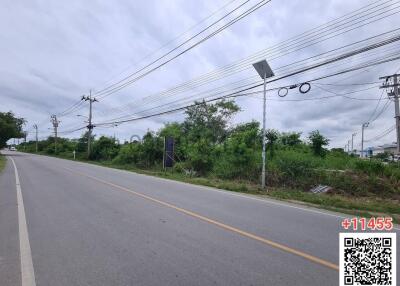 View of vacant land beside a paved road with streetlights and power lines
