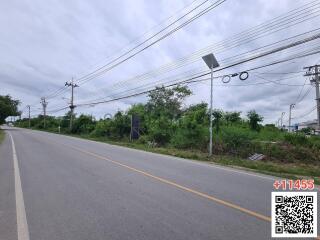 View of vacant land beside a paved road with streetlights and power lines