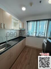 Modern kitchen with sleek black countertops, stainless steel appliances, and large window with blinds