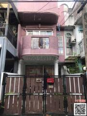 Front view of a residential building with a pink facade and gated entrance