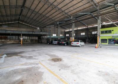 Spacious industrial building interior with multiple parked cars