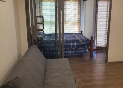 View of a cozy bedroom behind glass sliding doors with a comfortable sofa in the foreground