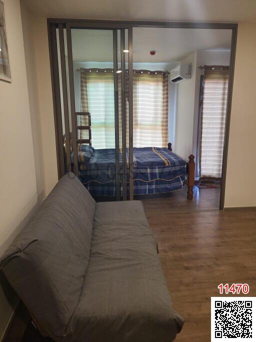View of a cozy bedroom behind glass sliding doors with a comfortable sofa in the foreground