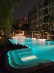 Elegant outdoor swimming pool with illuminated water and surrounding greenery at nighttime